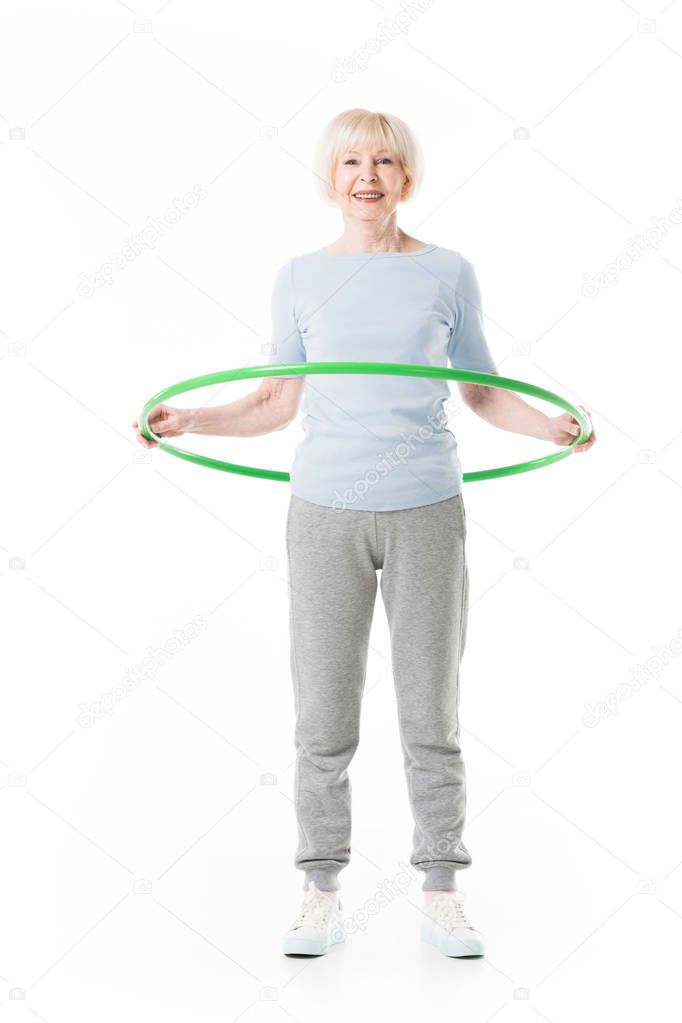 Smiling enior sportswoman doing hula hoop exercise isolated on white