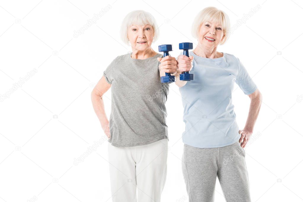 Two senior sportswomen doing exercise with dumbbell isolated on white