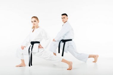 karate fighters stretching legs and looking at camera isolated on white clipart
