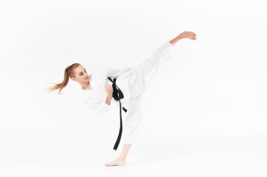 female karate fighter with black belt performing kick isolated on white clipart