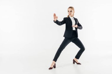 businesswoman in suit standing in karate position and looking away isolated on white clipart