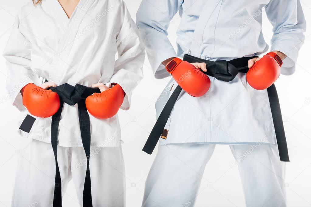 cropped image of karate fighters with black belts and red gloves isolated on white