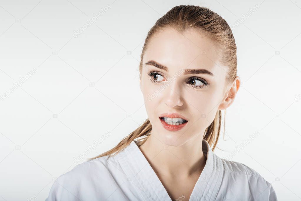 female karate fighter looking away with mouthguard isolated on white