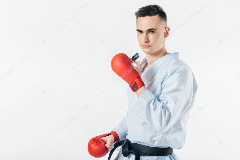 male karate fighter holding mouthguard and looking at camera isolated on white