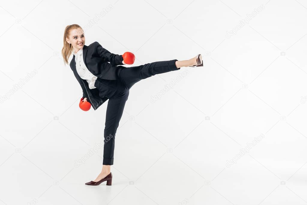 businesswoman performing kick in suit isolated on white