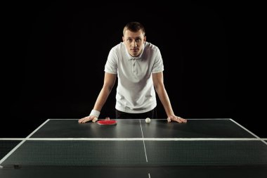 portrait of tennis player leaning on tennis table isolated on black clipart