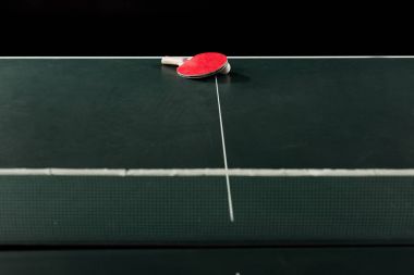close up view of tennis racket and ball on tennis table isolated on black clipart