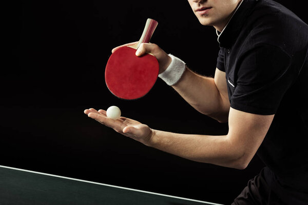 cropped shot of tennis player with tennis ball and racket in hands isolated on black