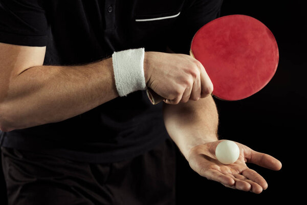 cropped shot of tennis player with tennis ball and racket in hands isolated on black