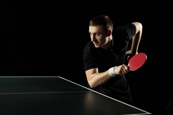 side view of young tennis player practicing in table tennis isolated on black