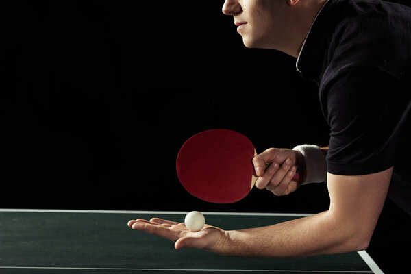 cropped shot of tennis player with tennis ball and racket in hands isolated on black