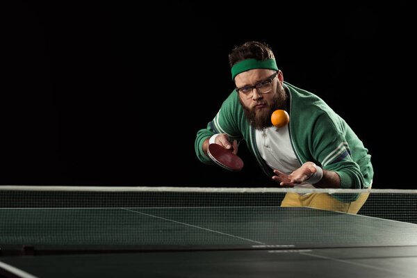 tennis player throwing up mandarin at tennis table isolated on black