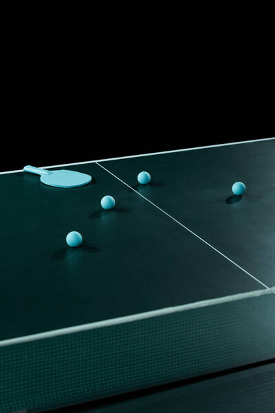 close up view of blue tennis racket and balls on tennis table isolated on black