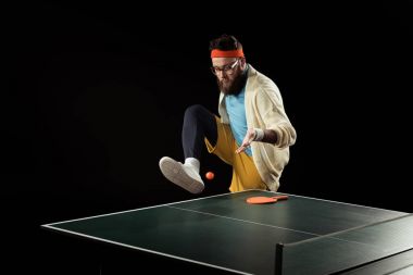 bearded tennis player playing with ball near tennis ball isolated on black clipart