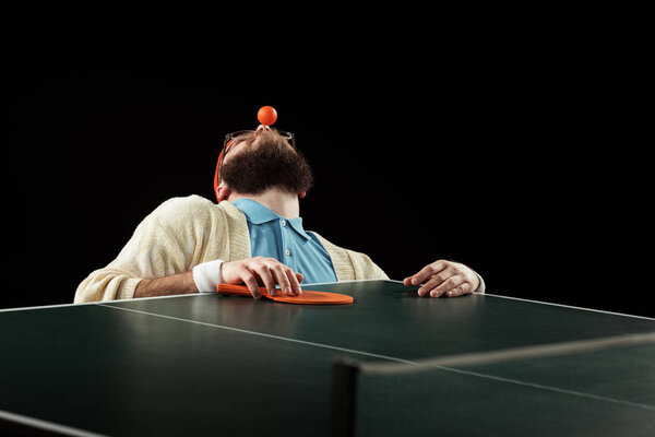 bearded tennis player holding ball on nose isolated on black