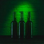 Three open green beer bottles in green light