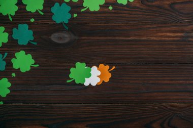 top view of clovers in colors of irish flag on wooden table clipart
