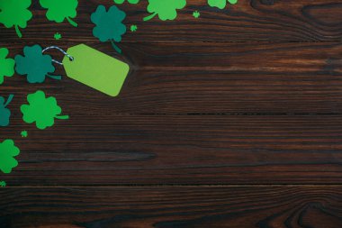top view of blank green label and shamrocks on wooden table clipart