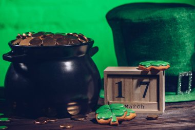 calendar, cookies in shape of shamrock, green irish hat and pot with golden coins, st patricks day concept clipart