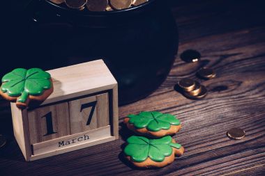 close-up view of calendar, cookies in shape of shamrock and pot with golden coins on wooden table   clipart