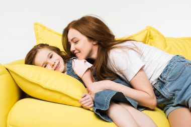Anne üzerinde beyaz izole kanepede gülümseyen küçük bir çocukla