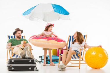 Happy little kid standing with flotation ring between parents sitting on sun loungers isolated on white, travel concept clipart