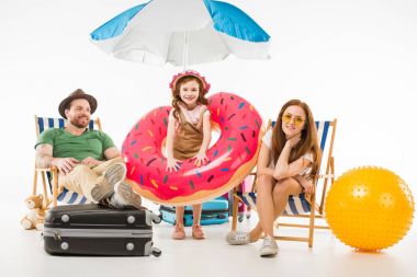 Little daughter with flotation ring standing between parents sitting on sun loungers isolated on white, travel concept clipart