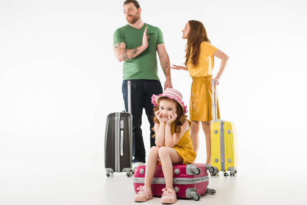 Upset little child sitting on suitcase while parents arguing isolated on white, travel concept