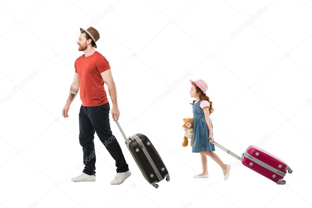 Father and daughter in hats carying suitcases isolated on white, travel concept