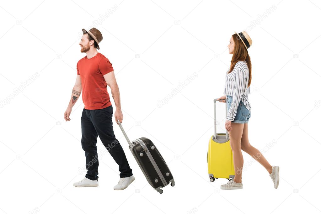 Stylish couple of tourists in hats carrying suitcases isolated on white, travel concept