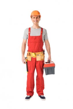 Smiling handyman in overalls holding toolbox isolated on white clipart