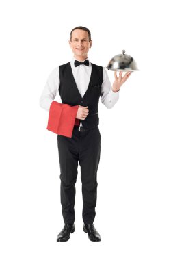 Smiling professional waiter holding serving tray with cover isolated on white clipart