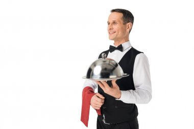 Smiling man in waiter uniform holding tray with cover isolated on white clipart