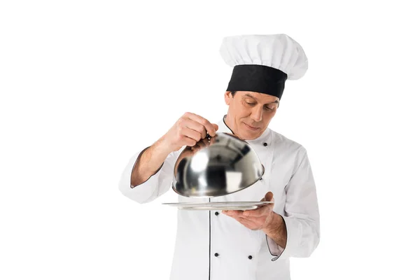 Mann Kochuniform Schaut Auf Tablett Mit Deckel Isoliert Auf Weiß — Stockfoto