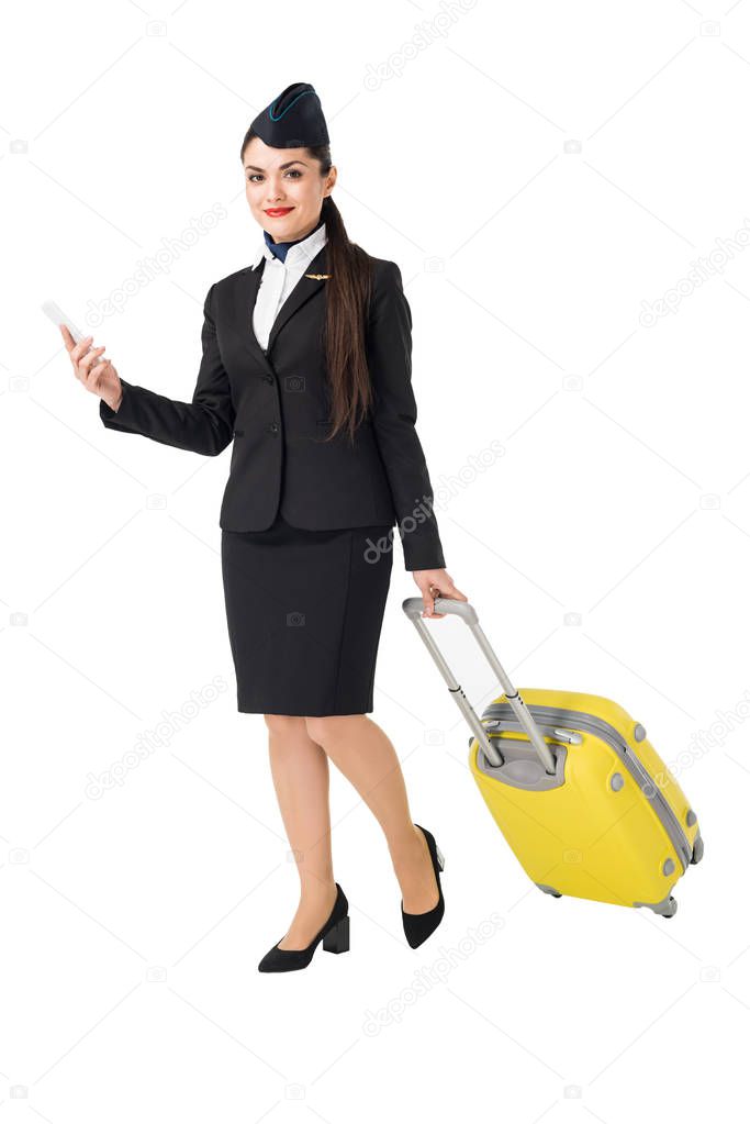 Young stewardess with suitcase using smartphone isolated on white