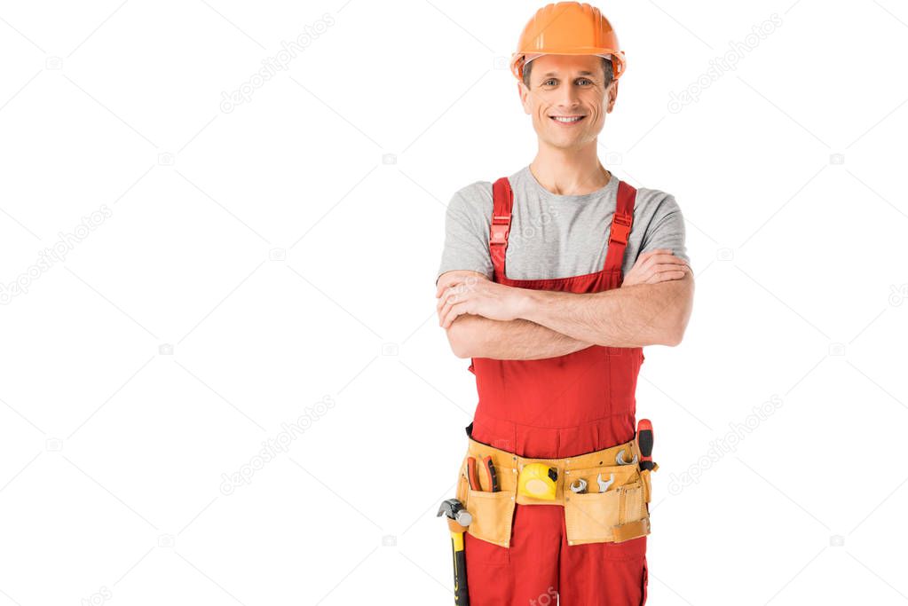 Cheerful construction worker in uniform with folded arms isolated on white
