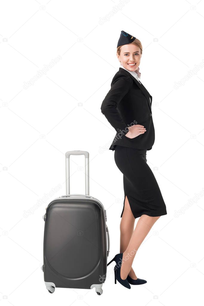 Young stewardess in uniform by suitcase isolated on white