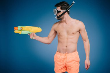 young man in shorts and diving mask holding water gun on blue  clipart