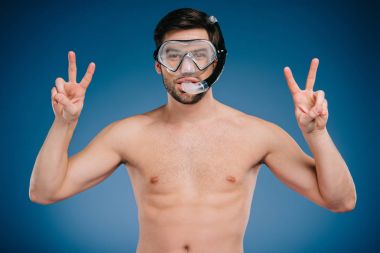 young man in snorkel and diving mask showing victory sign and looking at camera on blue clipart