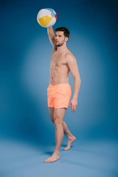 ビーチボールを投げ 青のよそ見のショート パンツで若い男が裸足の全長ビュー — ストック写真