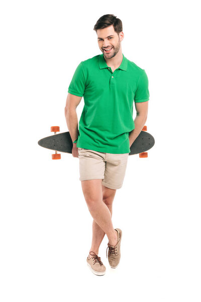 Красивый молодой человек держит скейтборд и улыбается в камеру, изолированную на белом
