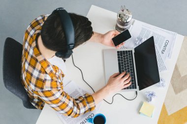 Laptop ve holding smartphone evde çalışma office genç serbest meslek