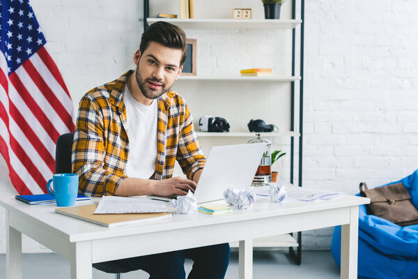 Man working by table with laptop in light office