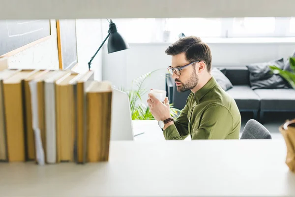 Young Man Looking Computer Screen Drinking Coffee Light Office — Free Stock Photo