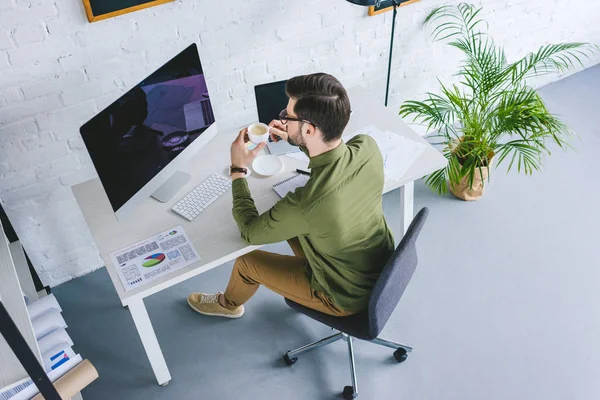 Junger Mann Schaut Auf Computerbildschirm Und Trinkt Kaffee Home Office — kostenloses Stockfoto