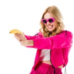 Young girl wearing pink shooting from banana isolated on white