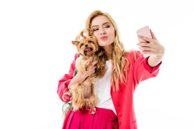 Young girl wearing pink suit holding cute Yorkshire terrier and taking selfie isolated on white clipart