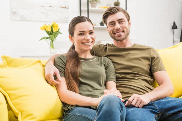 happy couple relaxing on comfy couch at home