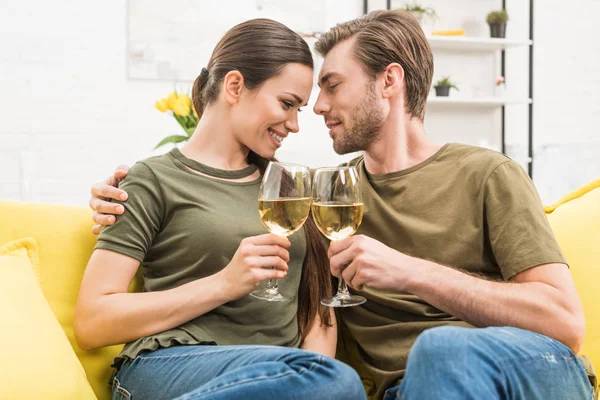 年轻拥抱夫妇一起喝葡萄酒在沙发上在家里 — 图库照片