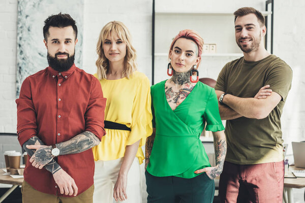 portrait of group of young stylish creative workers looking at camera in office